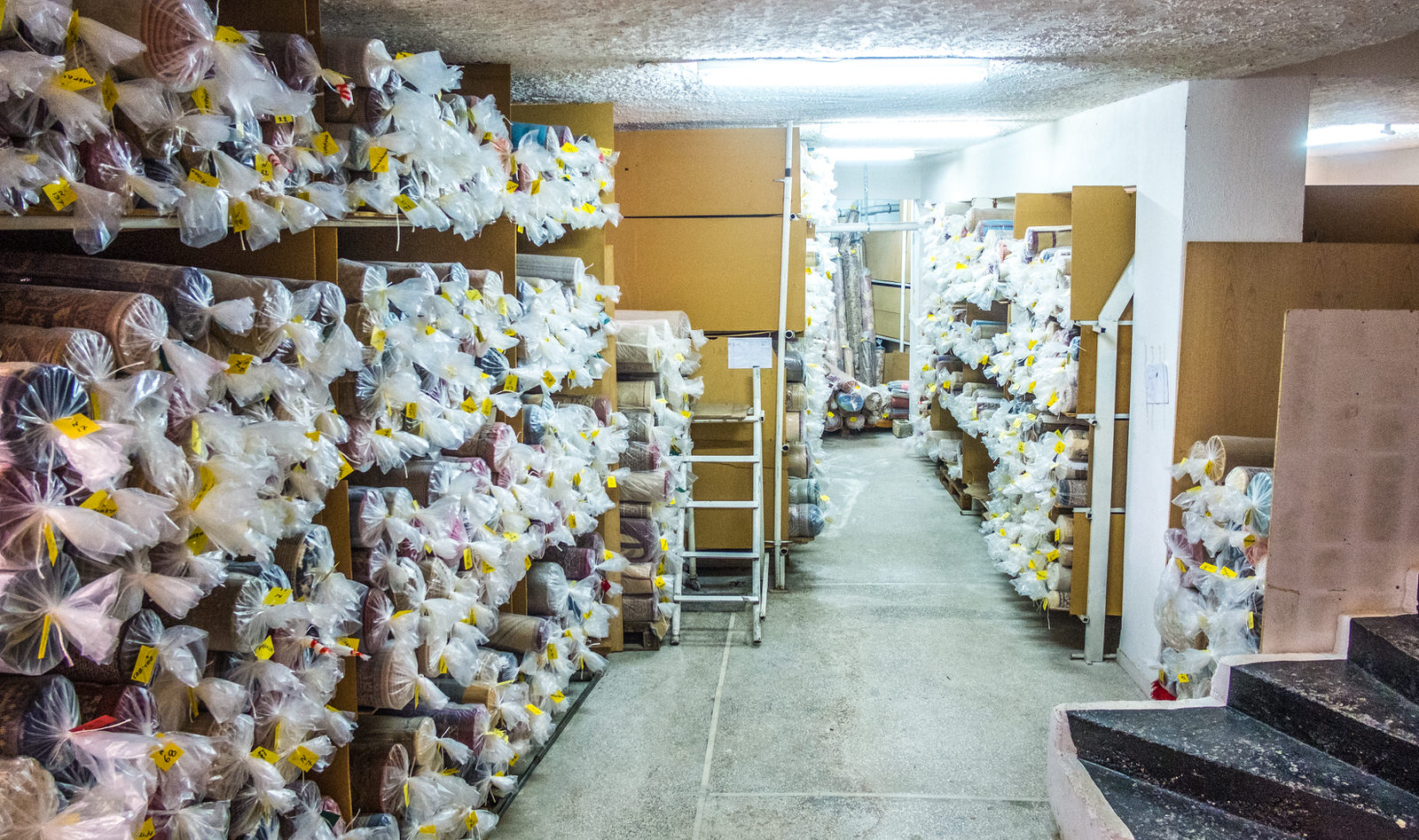 Αποθηκευτικός χώρος χαλιών: ράφια γεμάτα με καθαρά, συσκευασμένα χαλιά