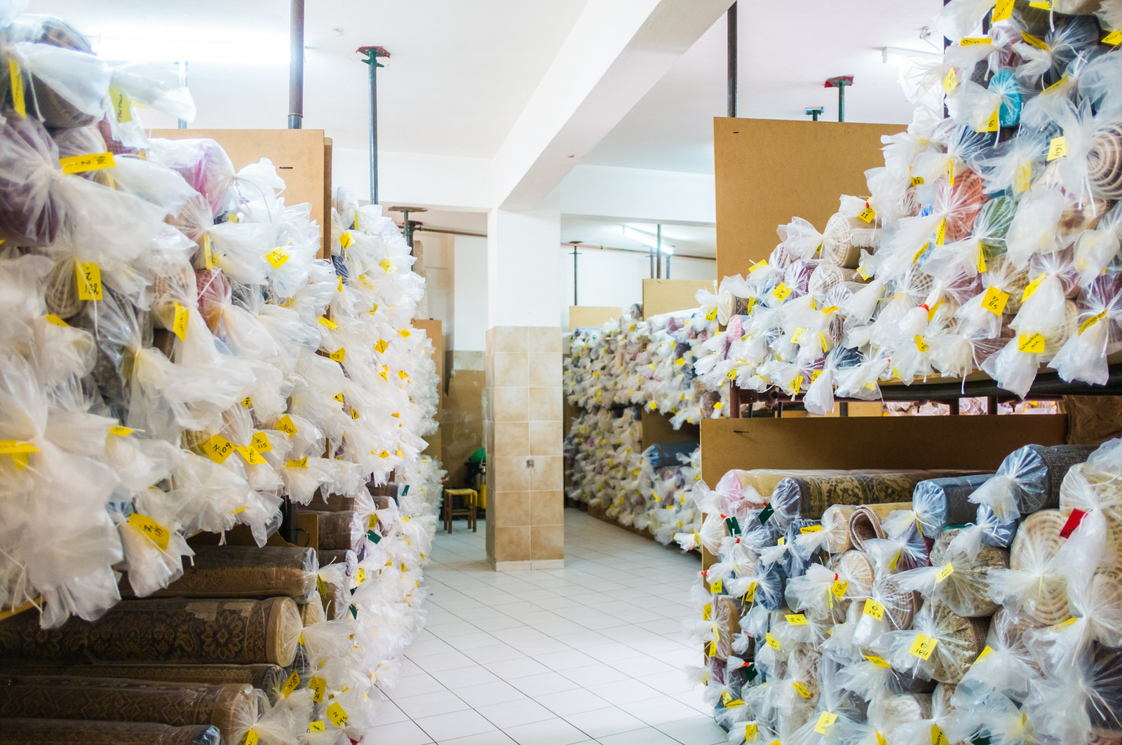 Αποθηκευτικός χώρος χαλιών: ράφια γεμάτα με καθαρά, συσκευασμένα χαλιά